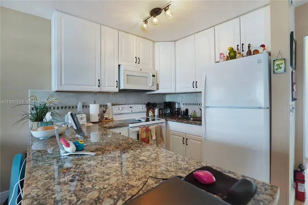 a kitchen with stainless steel appliances granite countertop a refrigerator sink and white cabinets