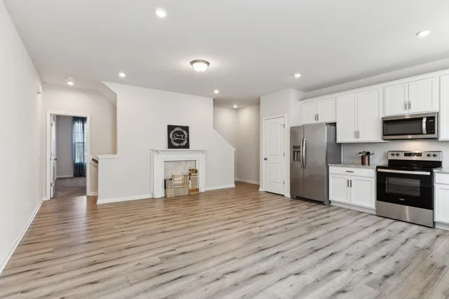 a view of an empty room with wooden floor and a fireplace