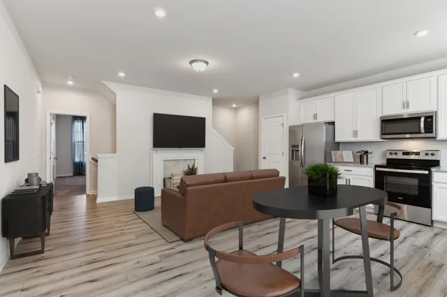 a living room with furniture a flat screen tv and kitchen view