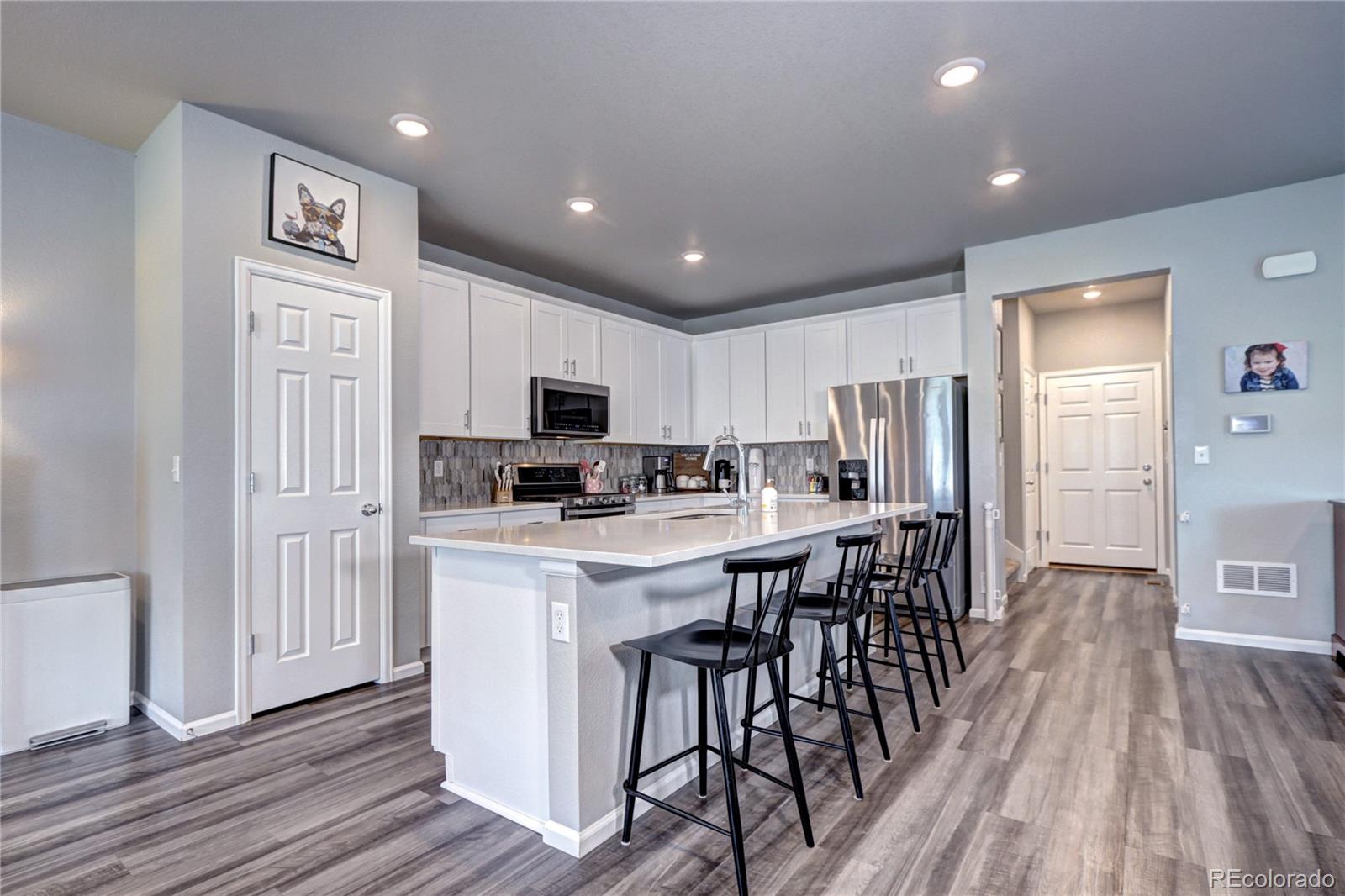 952 Morning Glory Road Brighton, CO 80640 - Photo 5 of 21 a kitchen with stainless steel appliances a microwave a stove a refrigerator a sink dishwasher a dining table and chairs with wooden floor