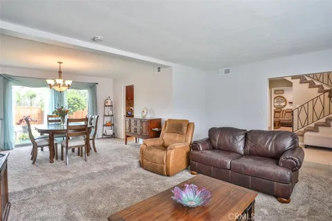 a living room with furniture kitchen view and a wooden floor