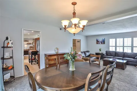 a dining room with wooden floor a chandelier a glass table and chairs