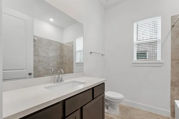 a bathroom with a sink a toilet a mirror and a window