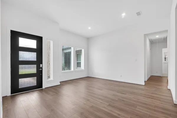 a view of an empty room with wooden floor and a window