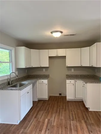 a kitchen with granite countertop white cabinets and wooden floor