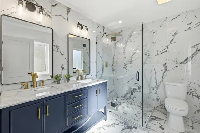 a bathroom with a granite countertop sink toilet mirror and shower