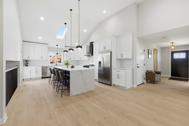 a kitchen with stainless steel appliances kitchen island refrigerator stove and white cabinets