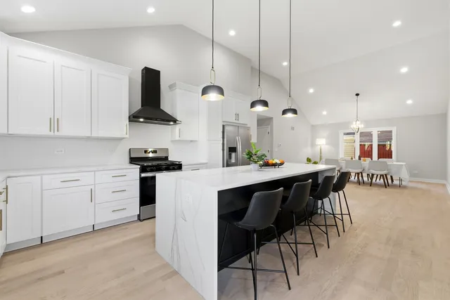 a kitchen with stainless steel appliances kitchen island granite countertop a table chairs sink and cabinets