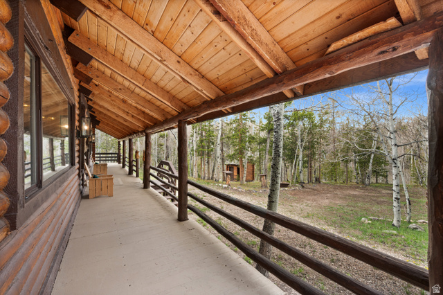 4725 Pine Ridge Road Evanston, UT 82930 - Photo 54 of 82 Expansive wrap-around porch featuring a log construction, exposed wood ceiling, rustic railing, and concrete flooring