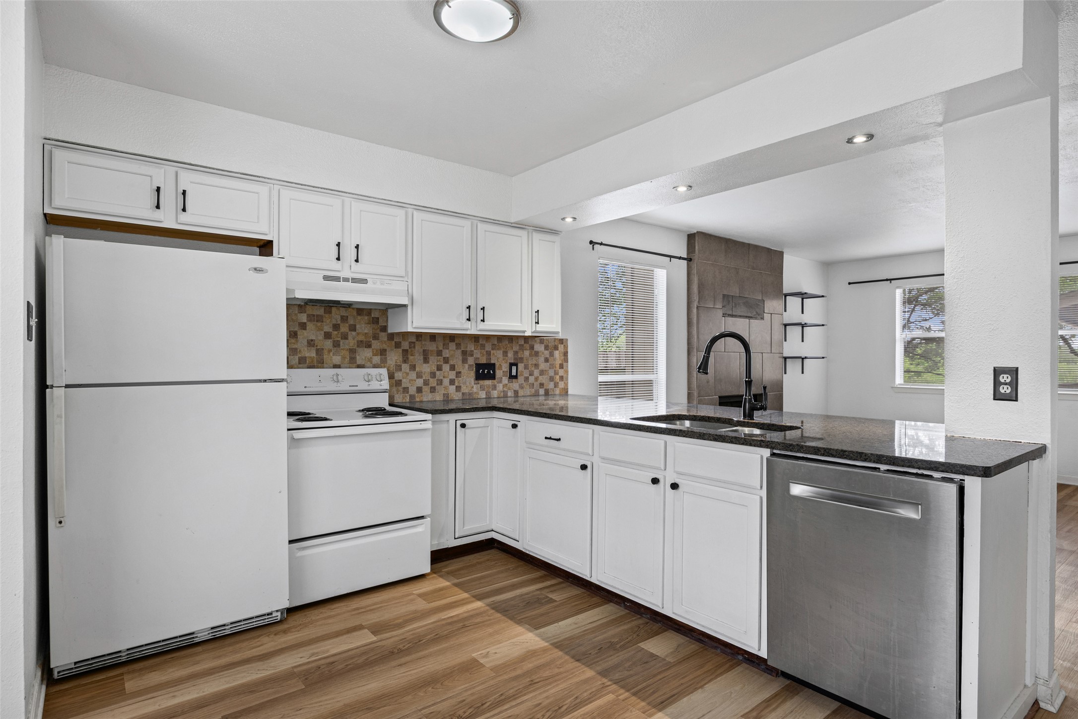8100 Dunn Street, Unit B Austin, TX 78745 - Photo 10 of 29 a kitchen with granite countertop white cabinets and white appliances