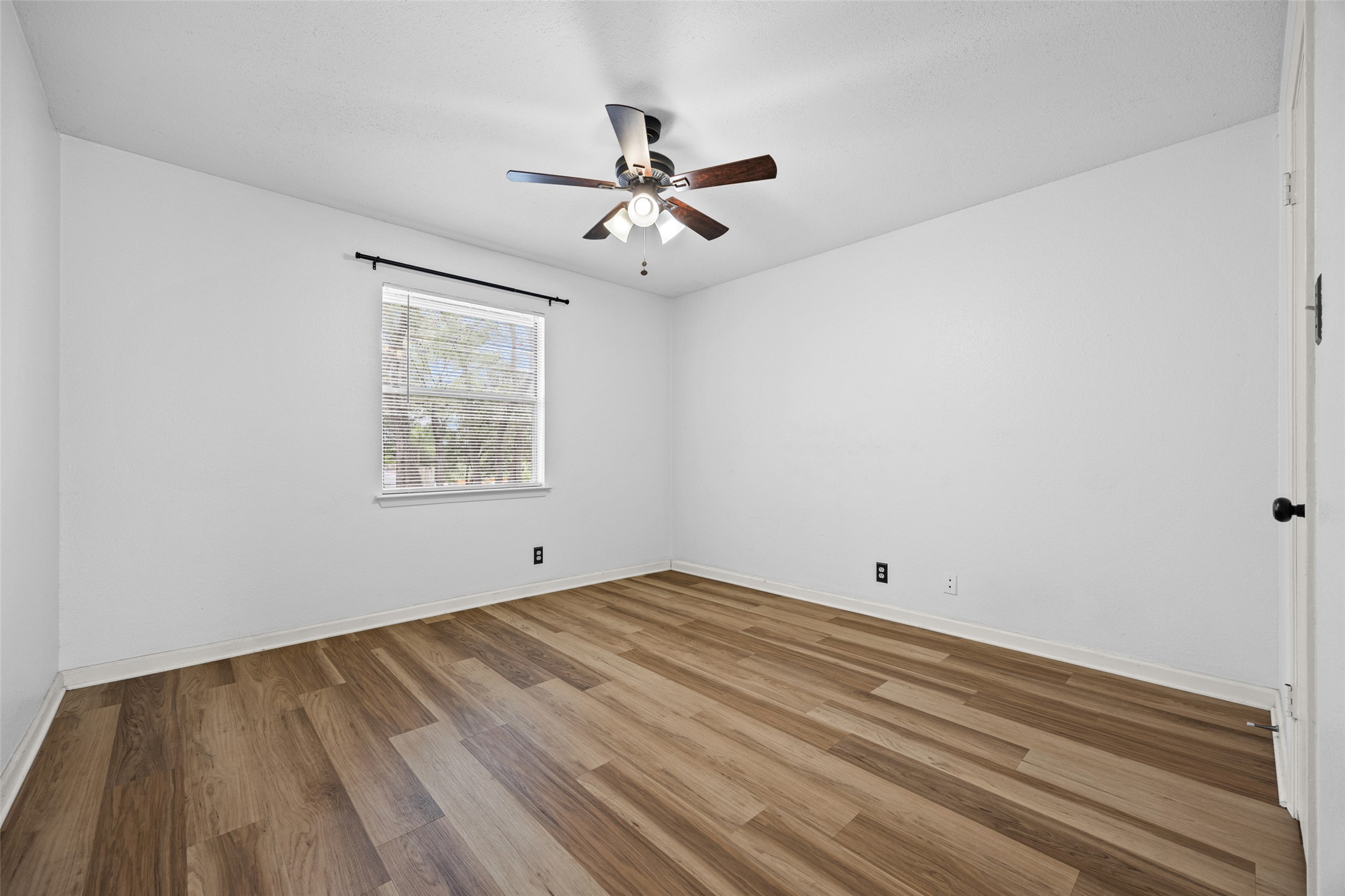 8100 Dunn Street, Unit B Austin, TX 78745 - Photo 16 of 29 an empty room with wooden floor ceiling fan and windows