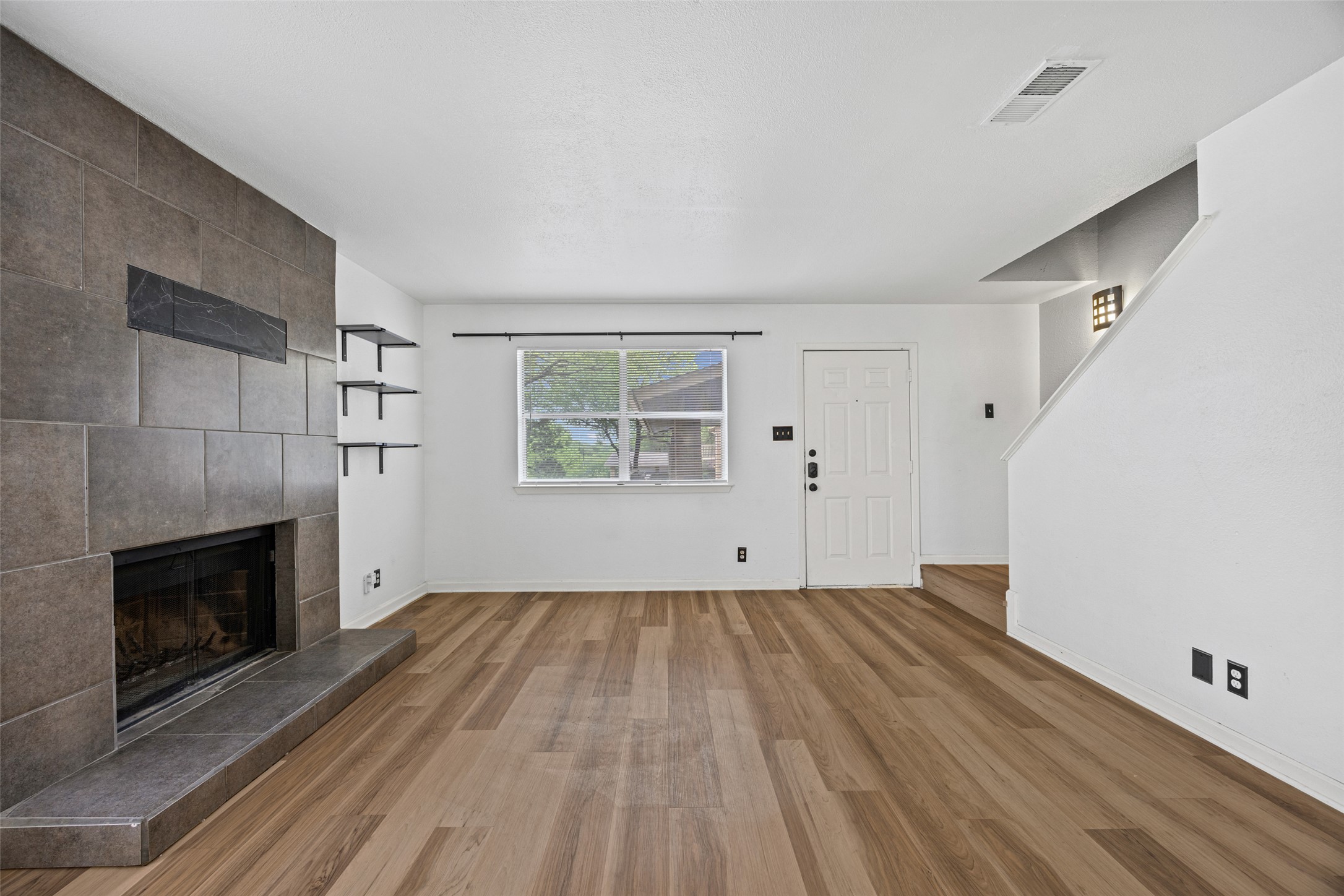 8100 Dunn Street, Unit B Austin, TX 78745 - Photo 2 of 29 an empty room with wooden floor fireplace and windows