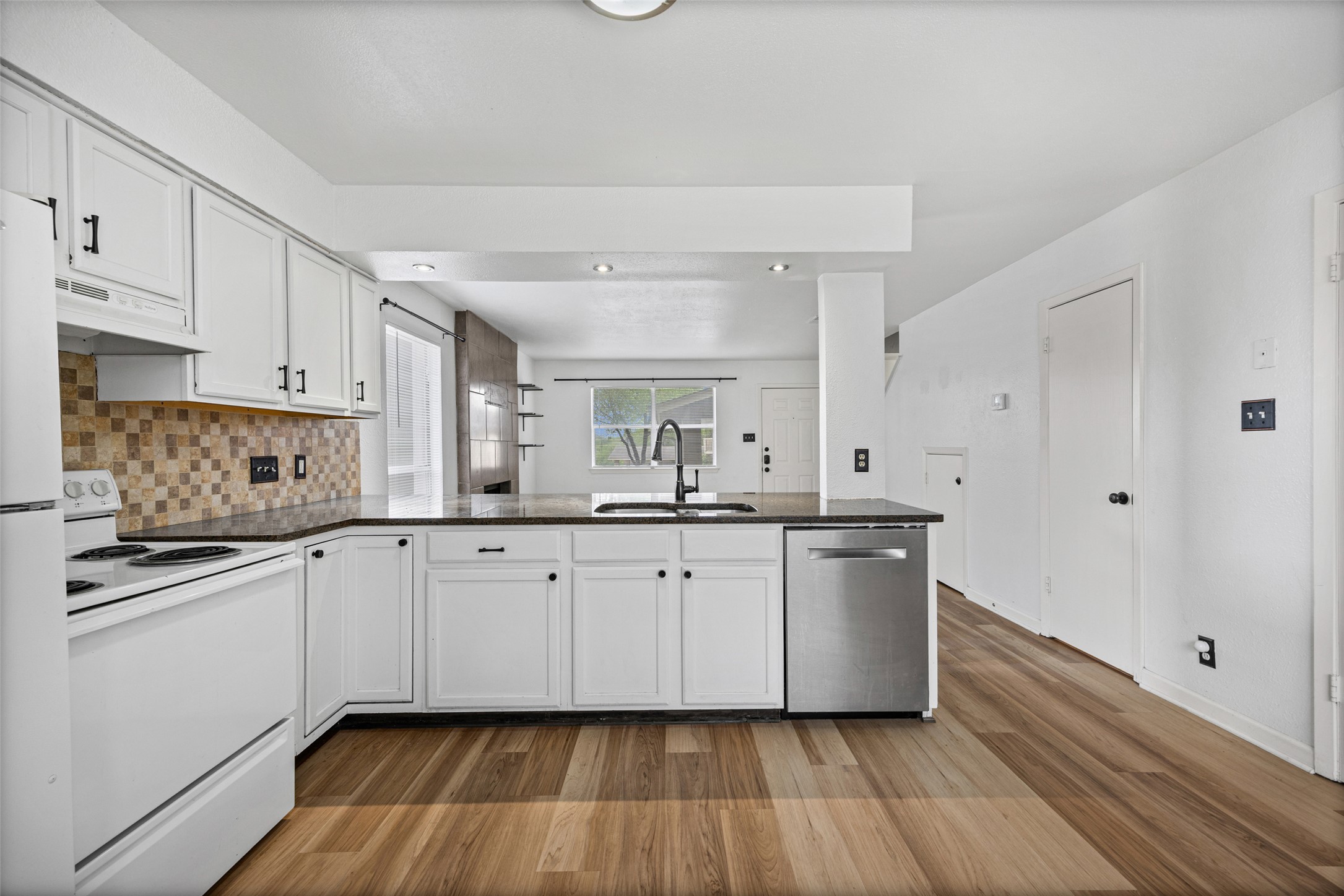 8100 Dunn Street, Unit B Austin, TX 78745 - Photo 9 of 29 a kitchen with stainless steel appliances white cabinets and wooden floors