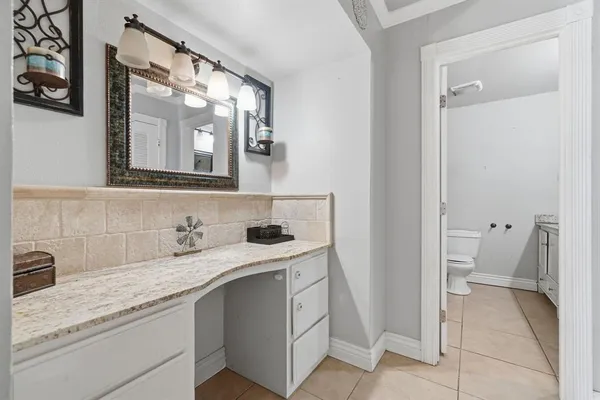 a en suite bathroom with a granite countertop sink and a mirror