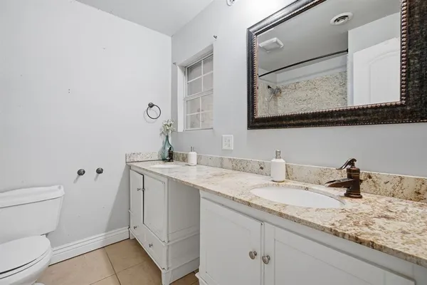 a bathroom with a granite countertop sink vanity mirror and toilet