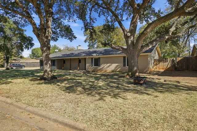 a backyard of a house with large trees and outdoor seating