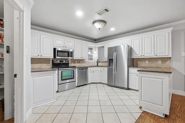 a kitchen with white cabinets stainless steel appliances and a counter space