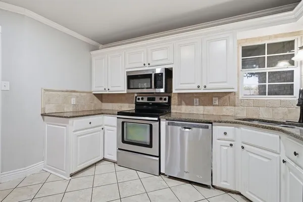 a kitchen with granite countertop white cabinets stainless steel appliances and a sink