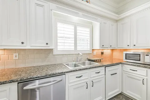 a kitchen with granite countertop white cabinets and white stainless steel appliances
