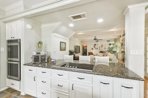 a living room with granite countertop white cabinets and stainless steel appliances