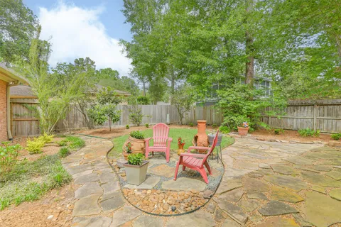 a view of a backyard with table and chairs potted plants and large tree