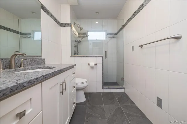 a bathroom with a granite countertop sink toilet and shower