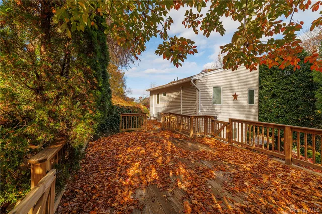 a view of backyard of house with wooden deck and outdoor seating