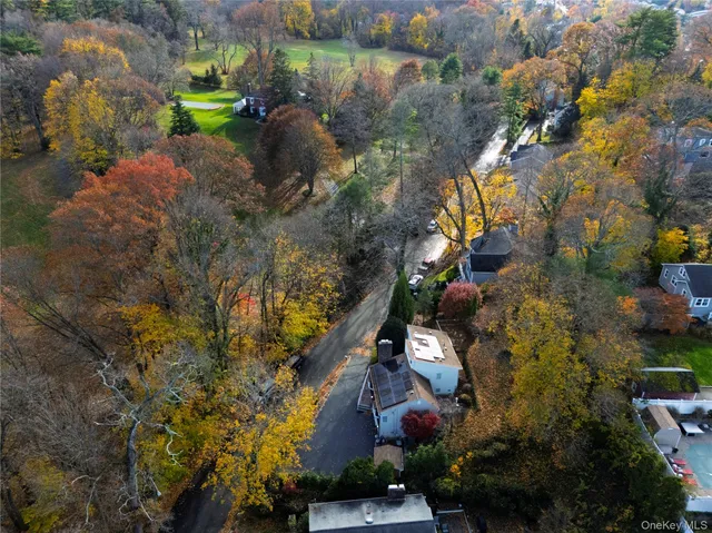 an aerial view of a house with a yard and large trees all around
