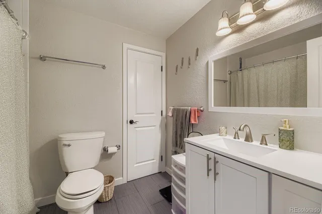 a bathroom with a toilet sink vanity and mirror