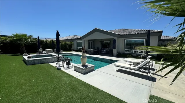 a view of a house with backyard sitting area and swimming pool