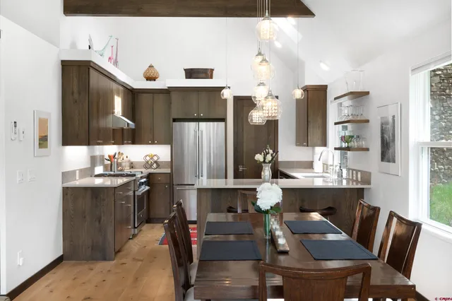 a kitchen with stainless steel appliances a dining table chairs refrigerator and cabinets