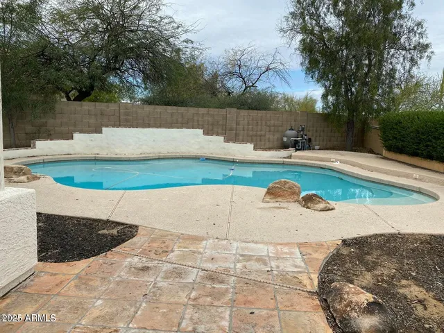 a view of a swimming pool with a patio and a yard