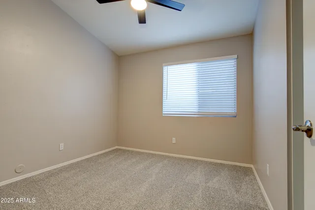 an empty room with a window and a ceiling fan