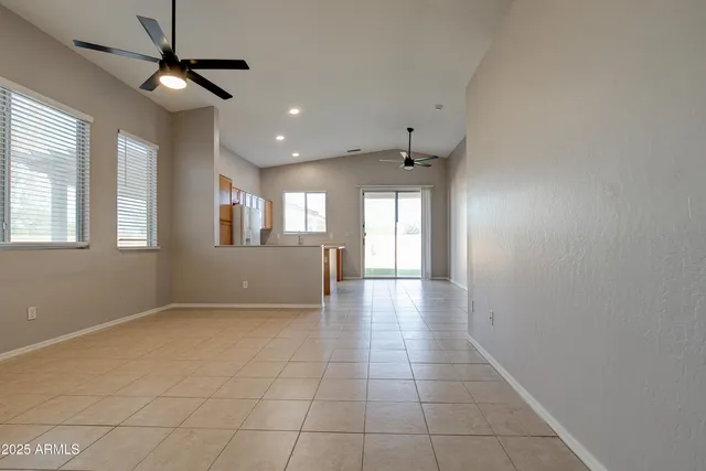 an empty room with windows fireplace and fan