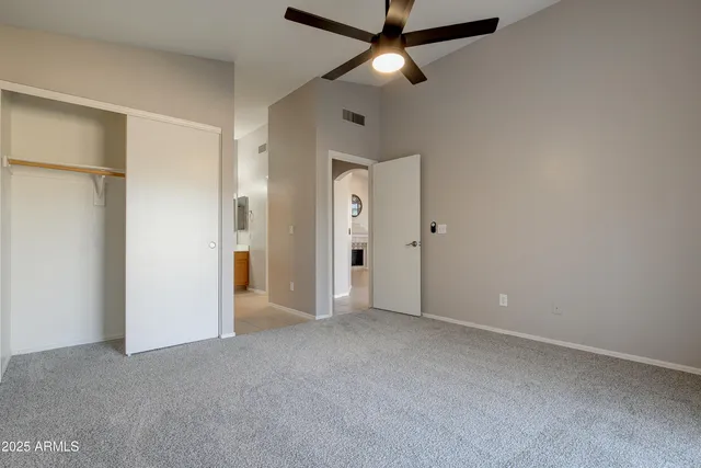 an empty room with windows and ceiling fan