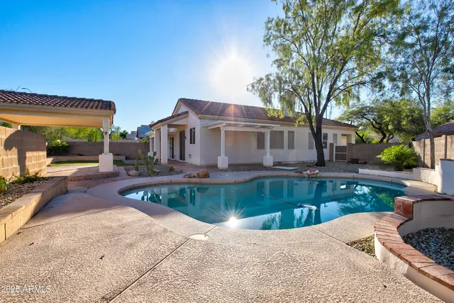 a view of a house with pool fire pit and a large tree