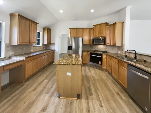 a large kitchen with stainless steel appliances granite countertop a stove refrigerator and a sink