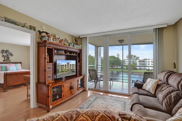 a living room with furniture a flat screen tv and a floor to ceiling window