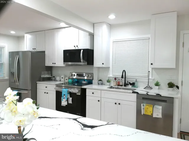 a kitchen with kitchen island a counter top space a sink stainless steel appliances and cabinets