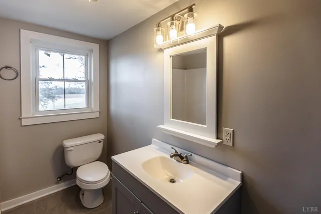 a bathroom with a toilet sink vanity and mirror