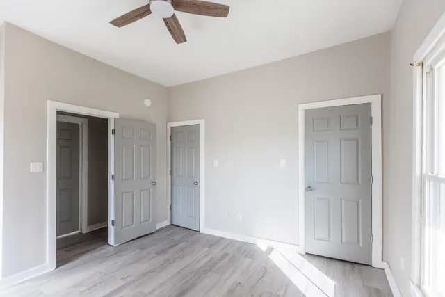 a view of empty room with wooden floor and ceiling fan