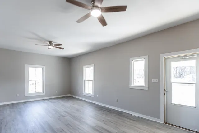 a view of an empty room with a window and wooden floor