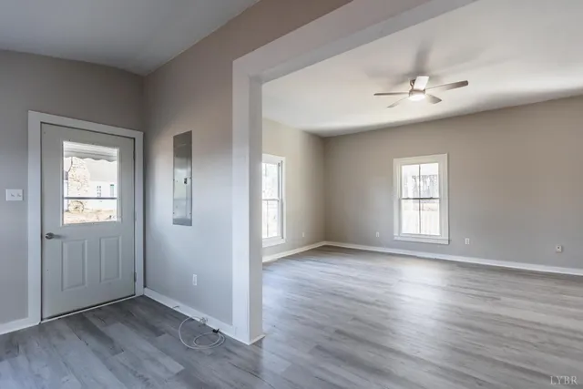 an empty room with wooden floor chandelier fan and windows