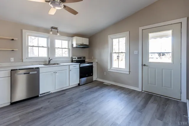 a kitchen with stainless steel appliances granite countertop a sink cabinets and wooden floors