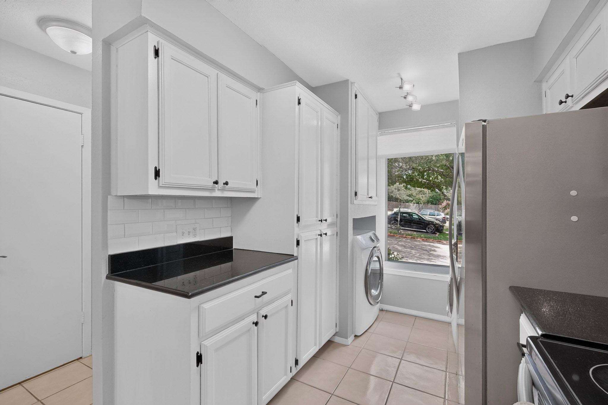 3801 Menchaca Road, Unit 25 Austin, TX 78704 - Photo 10 of 27 Kitchen with granite countertops, stainless steel appliances, and white cabinets; Washer and dryer nook