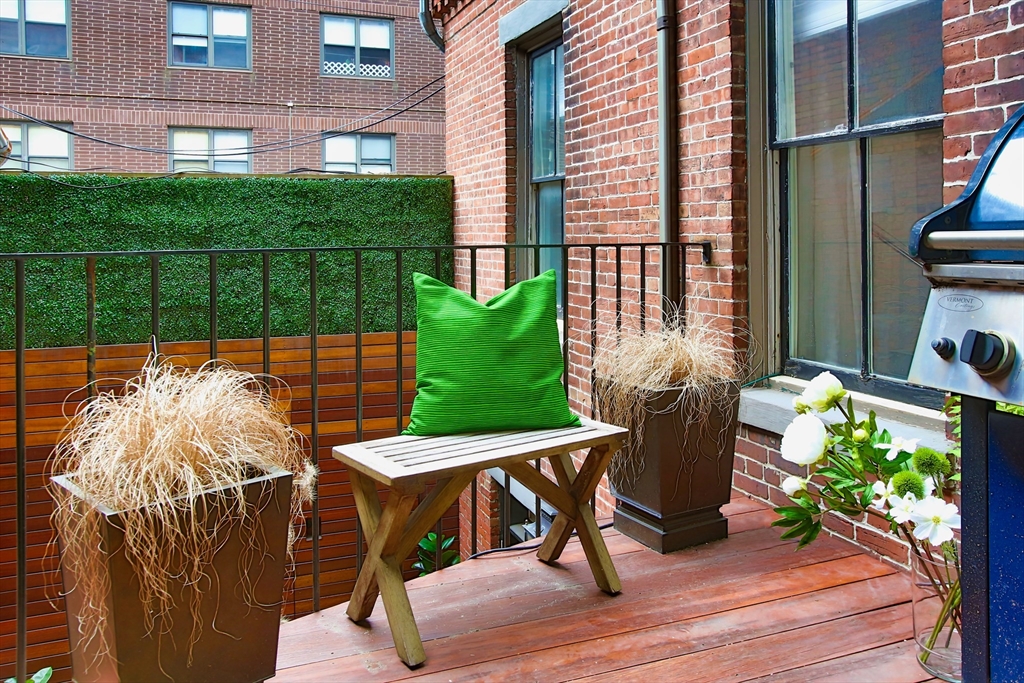 615 Massachusetts Avenue, Unit 2 Boston, MA 02118 - Photo 25 of 32 a view of a patio with table and chairs potted plants with wooden floor and fence