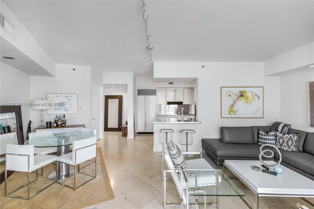 a living room with furniture a refrigerator and kitchen view