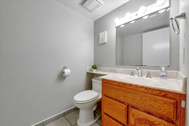 a bathroom with a granite countertop toilet sink and mirror