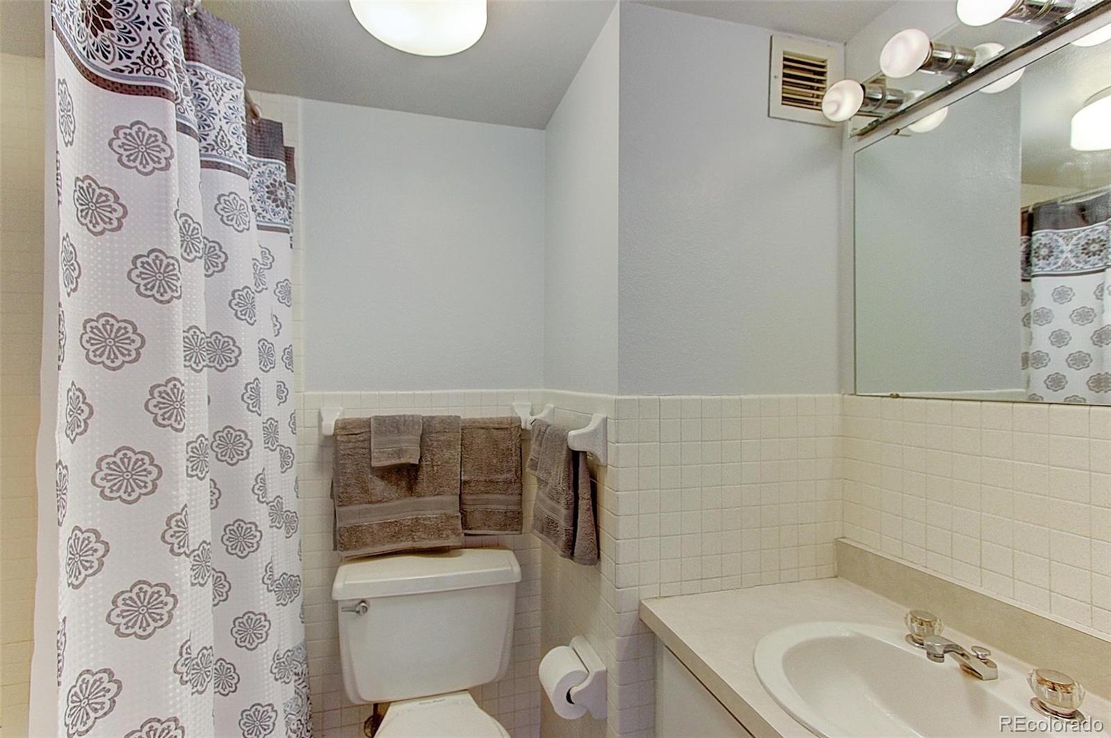 1020 15th Street, Unit 25B Denver, CO 80202 - Photo 7 of 33 a bathroom with a granite countertop toilet a sink and a mirror