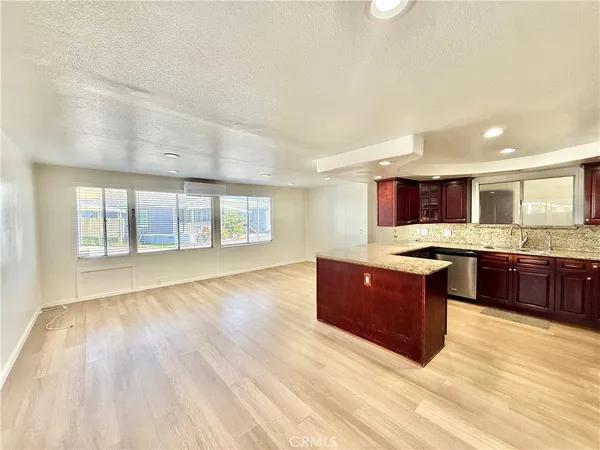 a living room with stainless steel appliances kitchen island granite countertop a stove and a large window